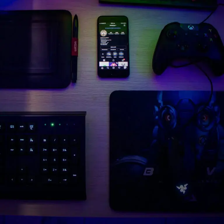 Table with a phone, game controller, keyboard and tablet on